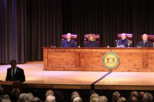 Gov. John Carney speaks while four members of the Delaware Supreme Court look on.