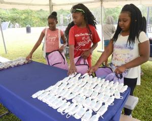 Jocelyn Gardner (l-r) Kimiah Brown and Denver Rivers load their bags with items.