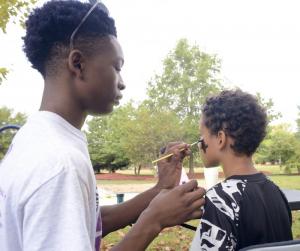 Jordan Gardner gets to work painting a cross on Shami Purnell’s face.