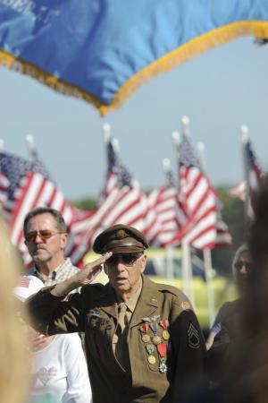 WW2 airplane radio operator Tom Creekmore salutes the flag during the ceremony.
