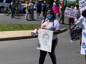 Alicia Hill leads protesters with a drawing of her brother, Brandon Roberts.