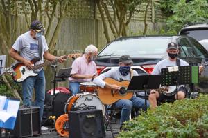 The Lewesers (pronounced "Losers") perform from Jackie Finer’s driveway. The band comprises Frank Powell on guitar, Chet Poslusny on guitar/banjo, Rob Putt on guitar, Owen Ridgley on bass, Rick Pfarr on guitar, Gerry Cohen on drums and Dennis Moriarty on banjo.