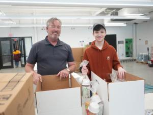 John Ridgely, left, and his son, Nathan, of Magnolia, smile at their spot in the assembly line at the Food Bank of Delaware Jan. 20.