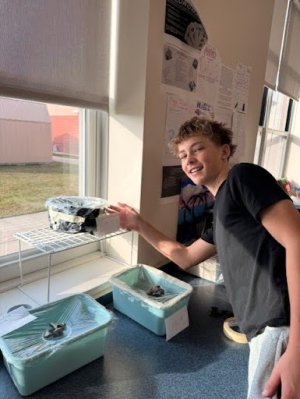 Brody Godbout shows his solar water still wrapped in a black garbage bag.