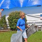 Donna Snajkowski removes debris from the front yard of her home. Most of her home's roof was blown off during the storm. BY RON MACARTHUR