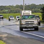 DelDOT crews assist motorists as they drive in water from a flooded stream near the Route 5-Beaver Dam Road intersection. BY RON MACARTHUR