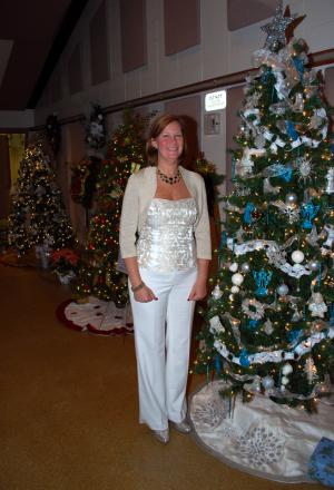 Peggy Dolby, assistant director of development with Delaware Hospice, stands beside some of the sponsored trees at the festival. BY MIKE LOVE