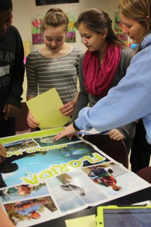 Mariner Middle students check out a poster promoting the Florida trip for which they are raising money. Pictured are (l-r) Jykiim Davis, Juliann Webb, Madilynn Natal and teacher Carly Zych. BY MELISSA STEELE